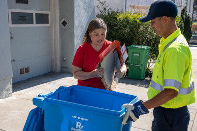 Recyclable material being handed to a collection crew member